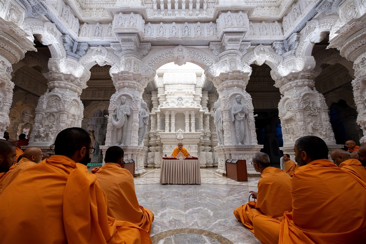 Swamishri doing puja in the Mukta Mandapam surrounded by a mesmerizing array of intricately carved sacred images