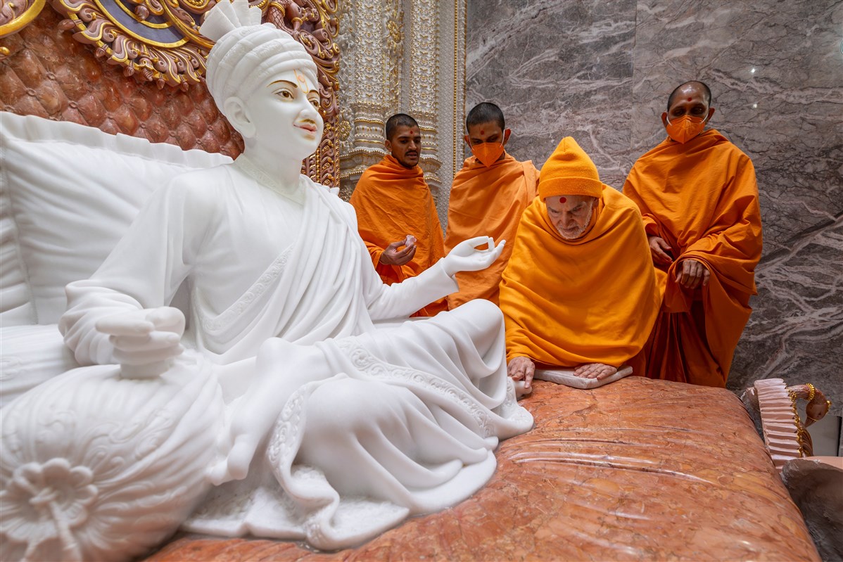 Swamishri touches the feet of Brahmaswarup Bhagatji Maharaj