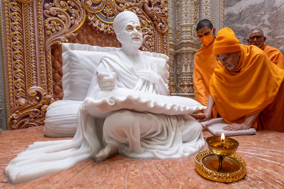 Swamishri touches the feet of Brahmaswarup Pramukh Swami Maharaj