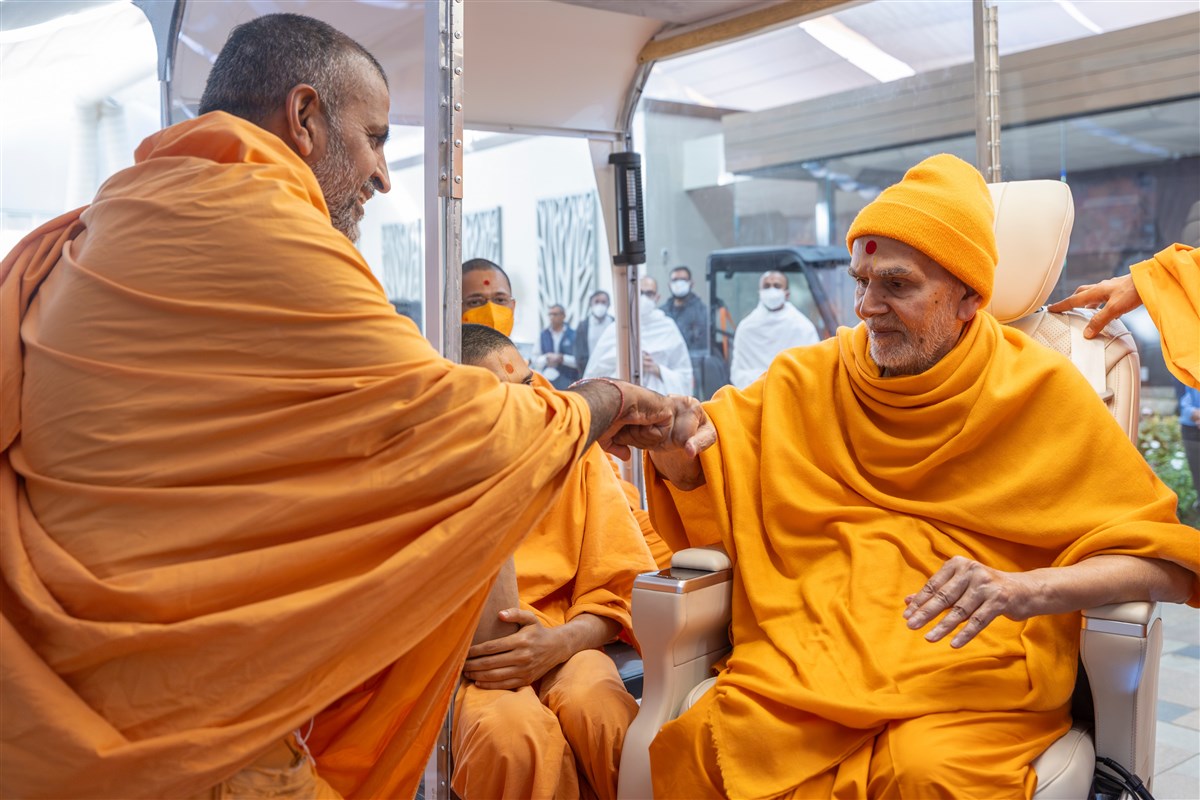 Swamishri gives a fist bump to a swami