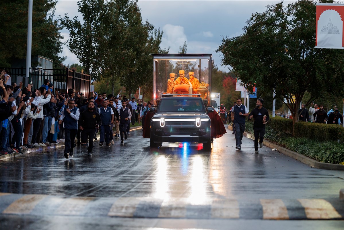 Swamishri's vehicle traverses the campus while devotees receive darshan