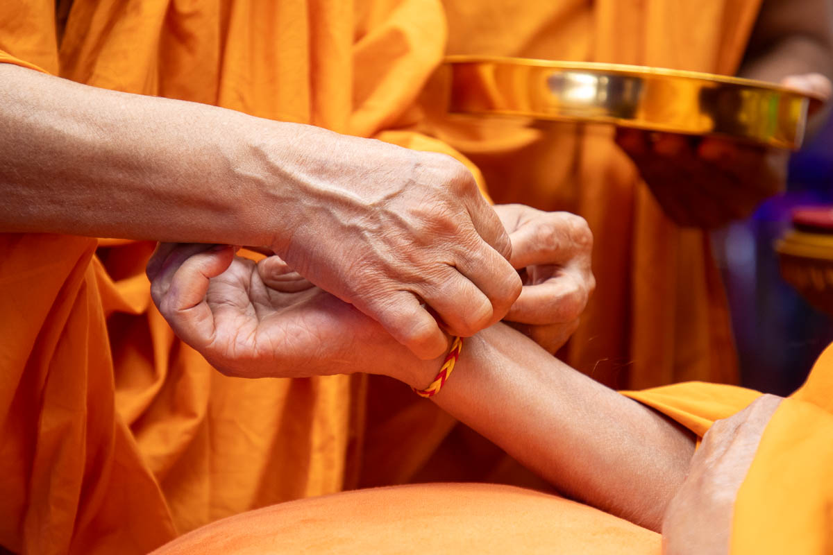 Pujya Ishwarcharan Swami ties a nadachhadi to Swamishri