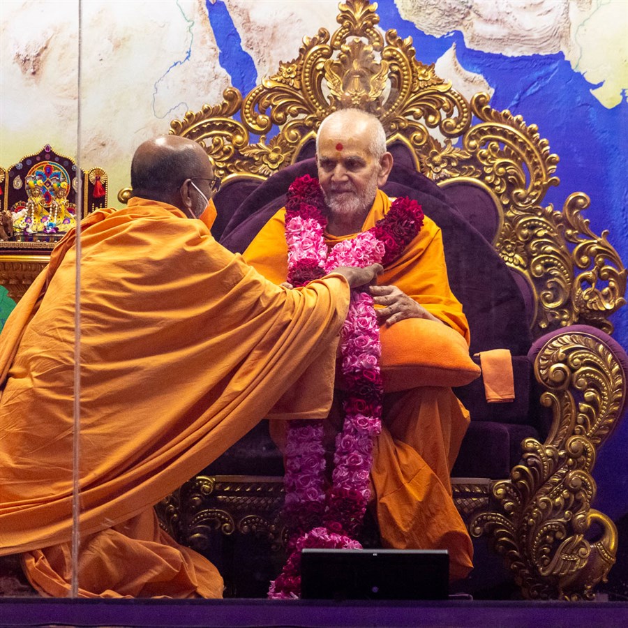 Dharmatilak Swami honors Swamishri with a garland