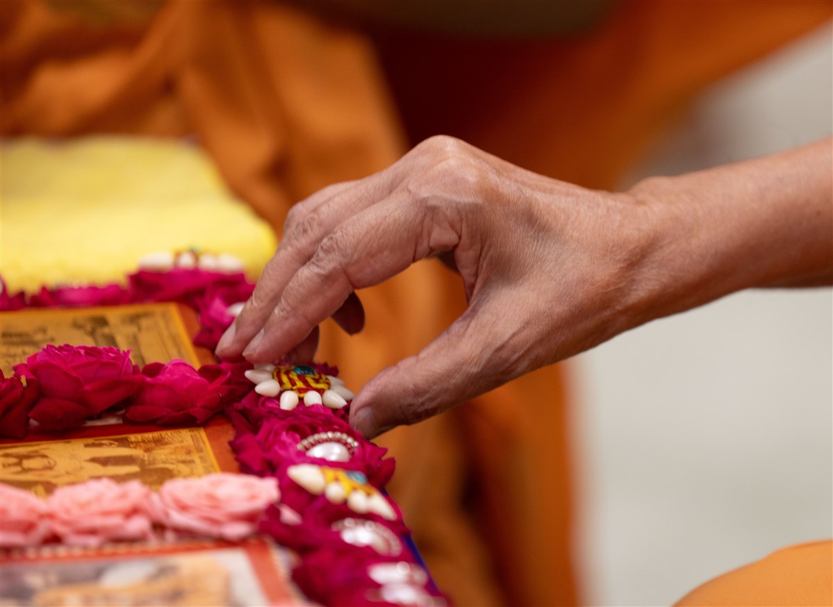Swamishri adjusts a flower