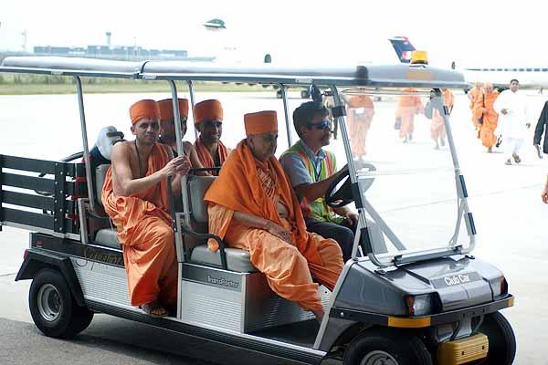Swamishri arrives at the airport lounge in a golf cart 	