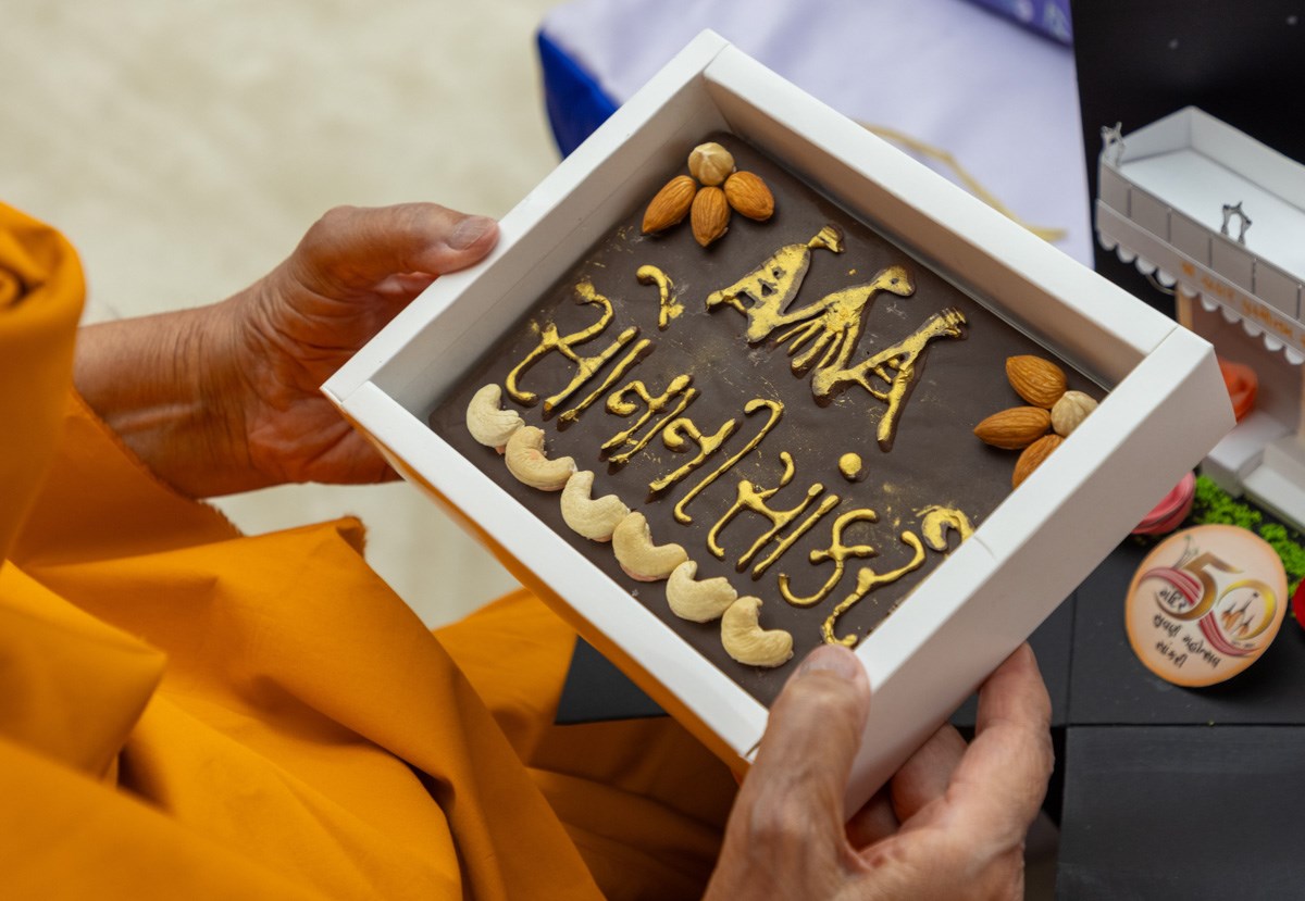 Swamishri observes a decorated chocolate commemorating the 50th anniversary of the BAPS Mandir in Sankari