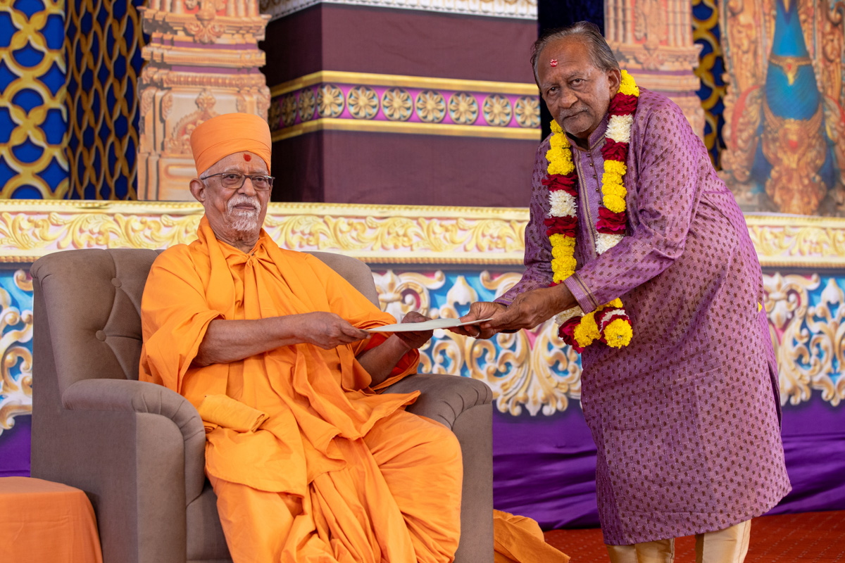 Pujya Doctor Swami gives a memento to a newly initiated parshad's father