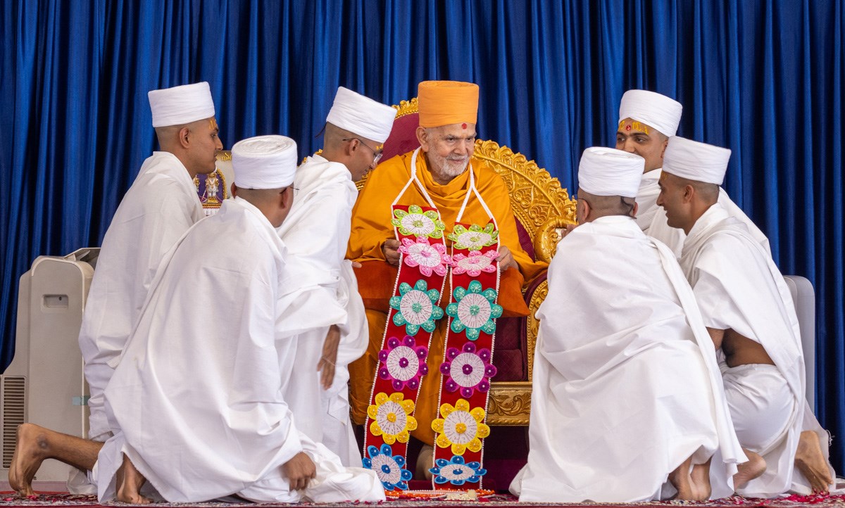 Newly initiated parshads honor Swamishri with a garland