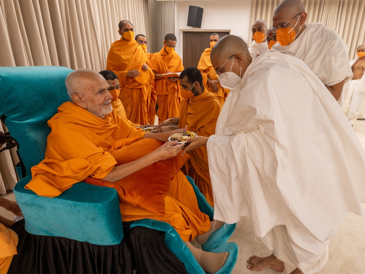 Swamishri gives prasad to newly initiated parshads