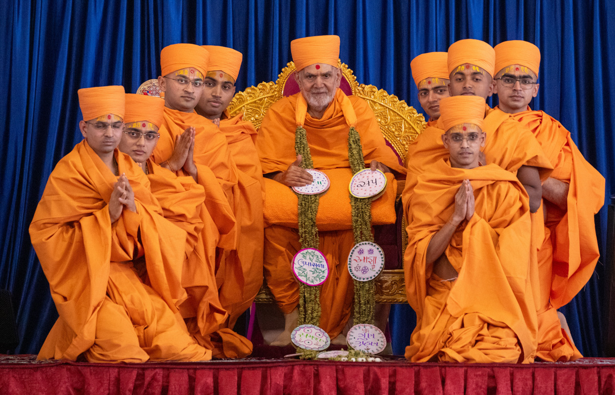 Newly initiated swamis honor Swamishri with a garland