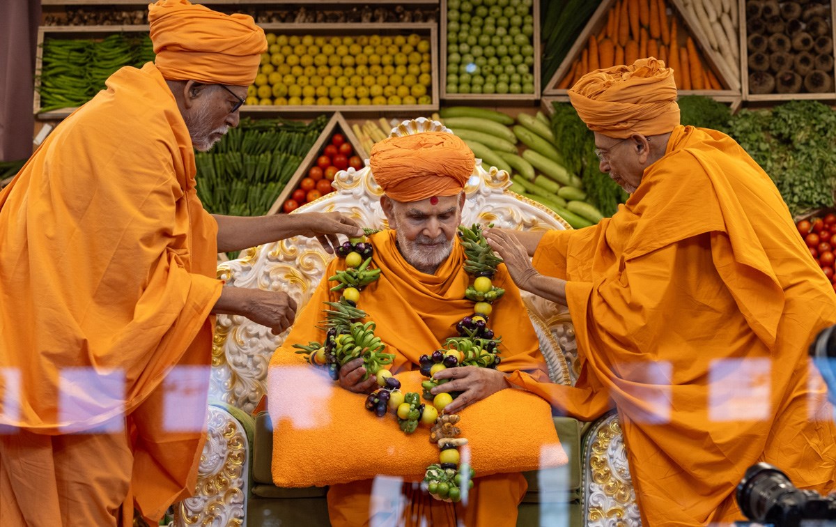 Pujya Tyagvallabh Swami and Pujya Bhaktipriya Swami (Pujya Kothari Swami) honor Swamishri with a vegetable garland