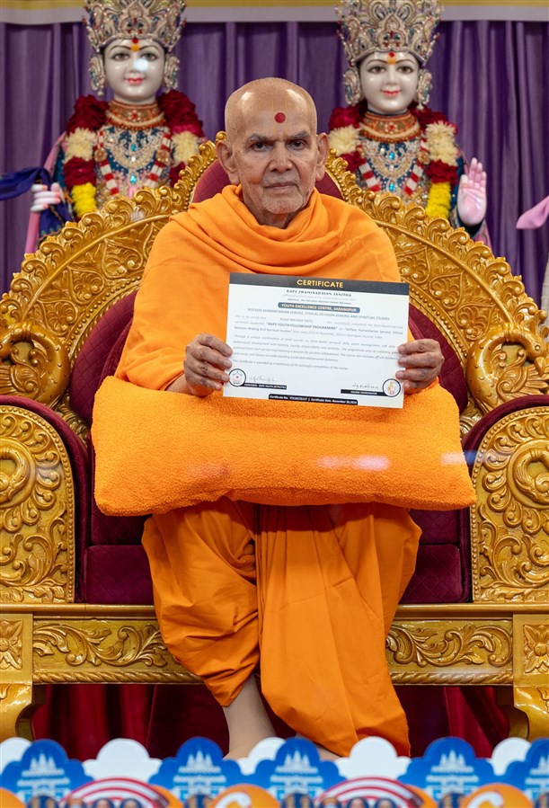 Swamishri sanctifies a certificate to be presented to the youths of the YTK