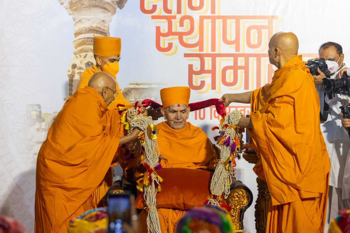 Pujya Tyagvallabh Swami and Pujya Viveksagar Swami honor Swamishri with a garland