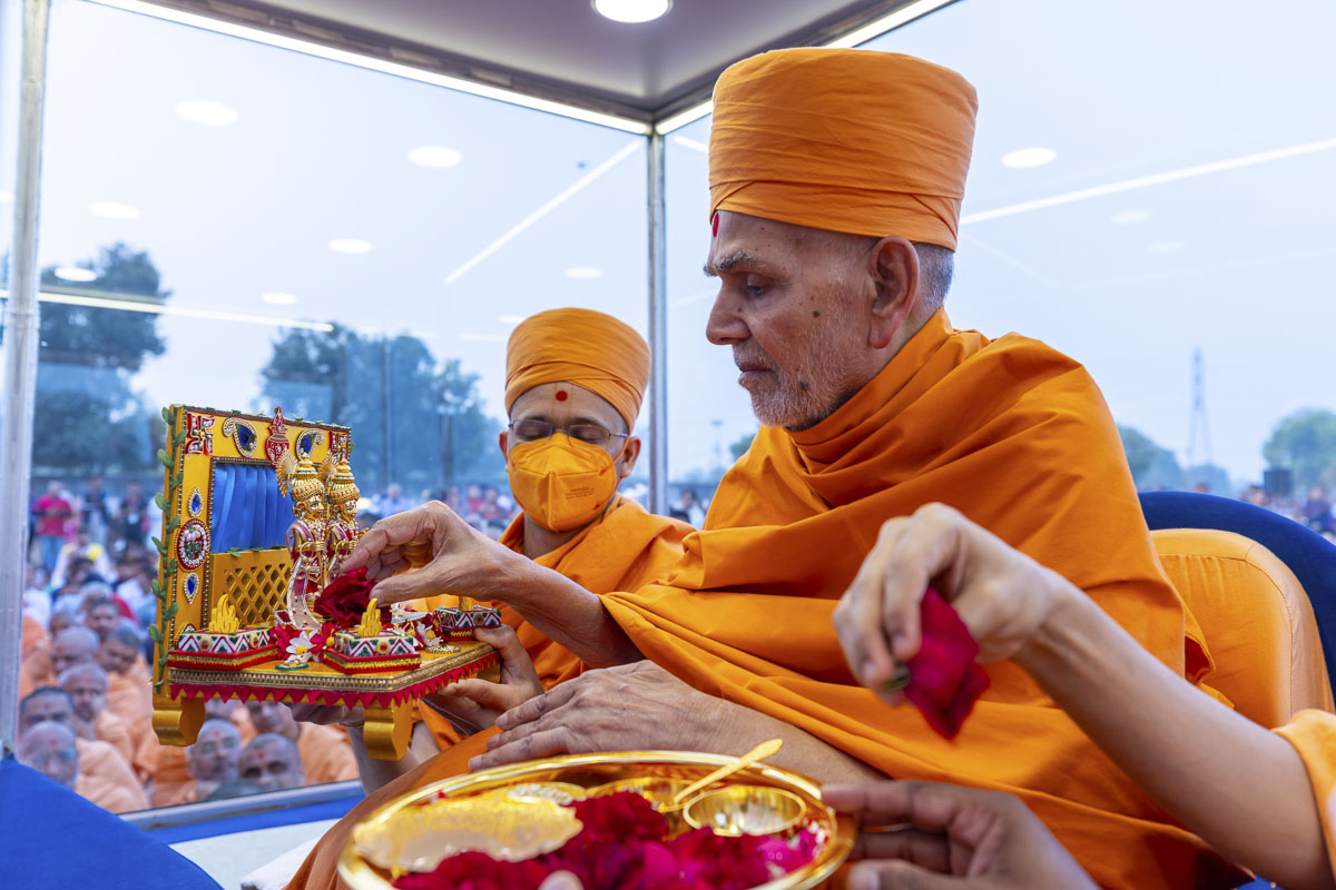 Swamishri offers a flower to Shri Harikrishna Maharaj and Shri Gunatitanand Swami Maharaj