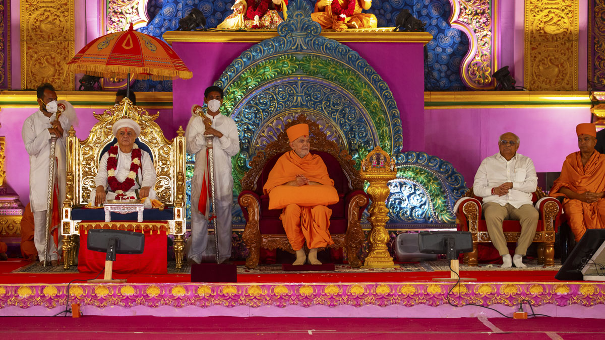 Swamishri, Pujya Acharya Avichaldasji Maharaj and Shri Bhupendrabhai Patel on the stage during the assembly. For more photos of the event, please click <a href='https://www.baps.org/Photos/2023/Murti-Pratishtha-Assembly-28838.aspx?mid=255756' target='blank' style='text-decoration:underline; color:blue;'>here</a>