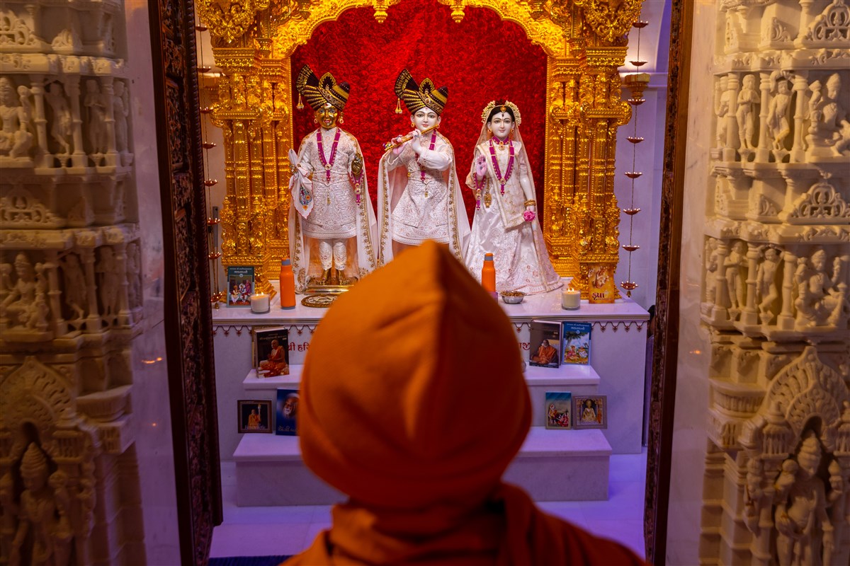 Swamishri engrossed in darshan of Shri Harikrishna Maharaj, and Shri Krishna Bhagwan and Radhaji