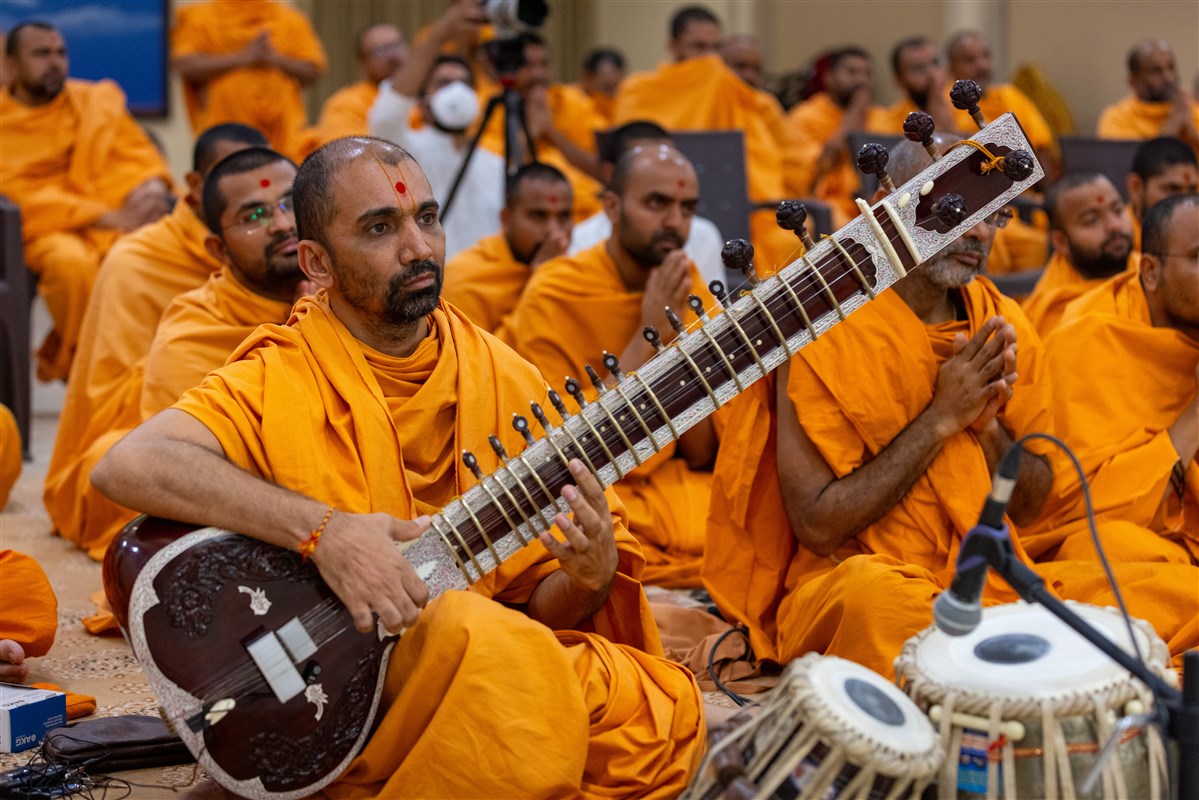 A swami plays the sitar during Swamishri's puja