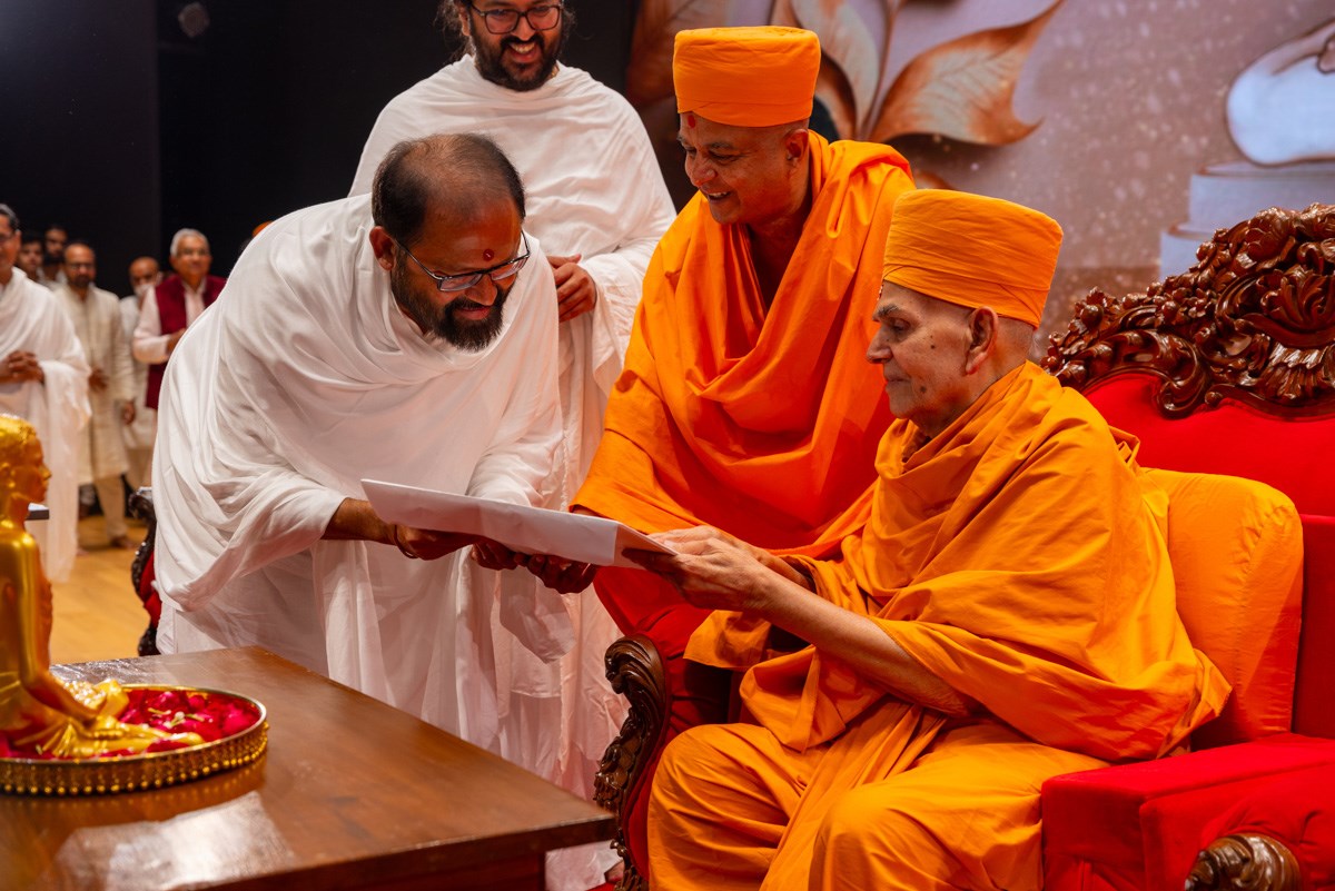 Swamishri gives an invitation to Pujya Gurudevshri Rakeshji for the inauguration ceremony of BAPS Hindu Mandir, Abu Dhabi
