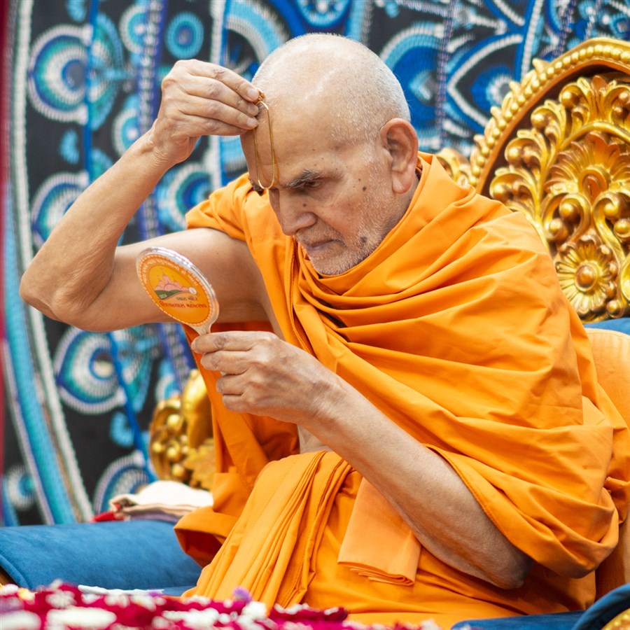 Swamishri applies a tilak on his forehead at the start of his daily puja