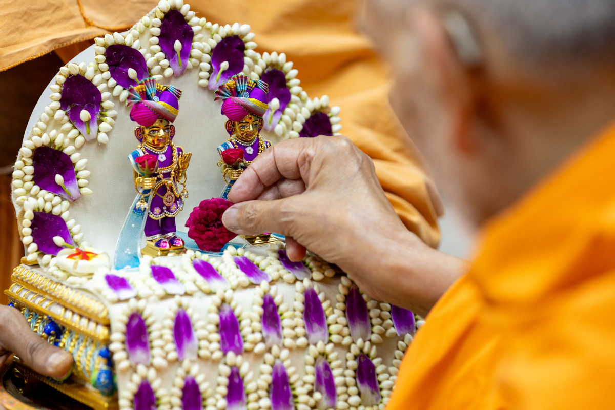 Swamishri offers a flower to Shri Harikrishna Maharaj and Shri Gunatitanand Swami Maharaj