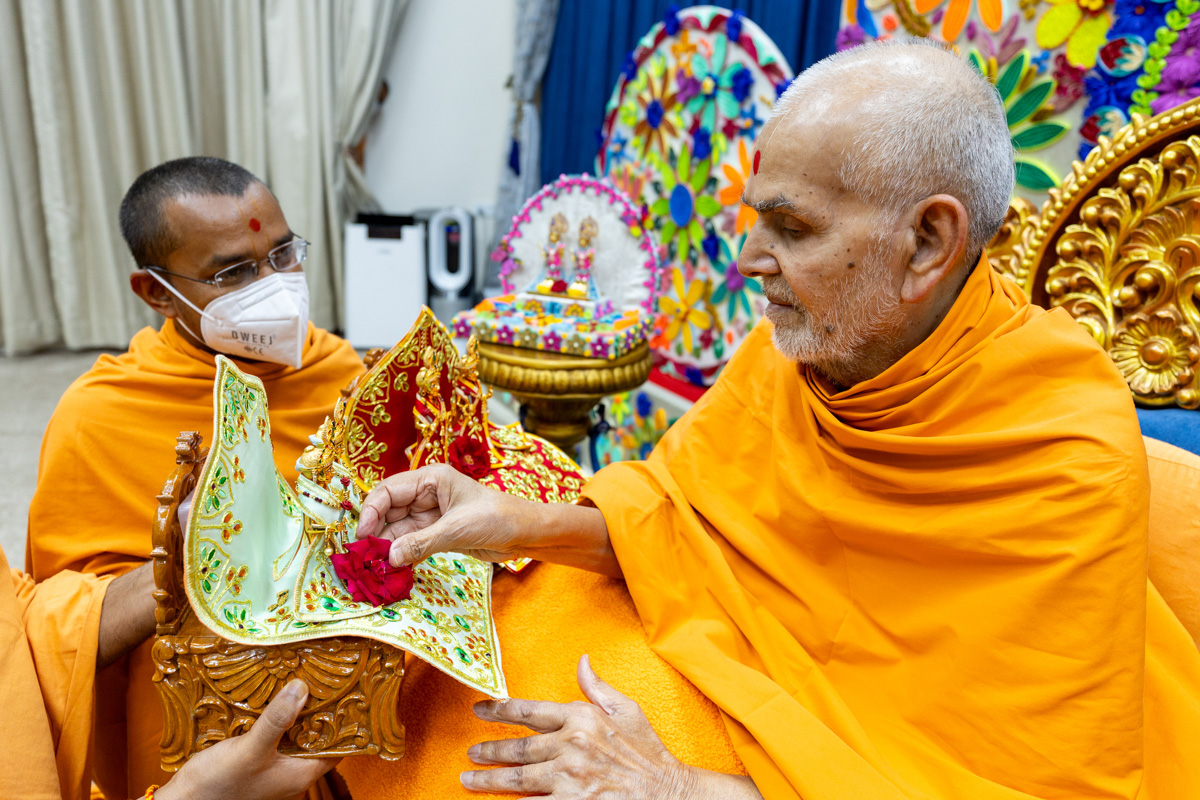 Swamishri offers a flower to Shri Akshar-Purushottam Maharaj