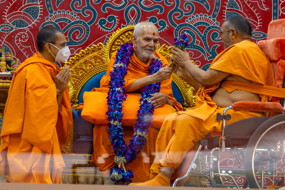 Narendraprasad Swami honors Swamishri with a garland and a chhadi