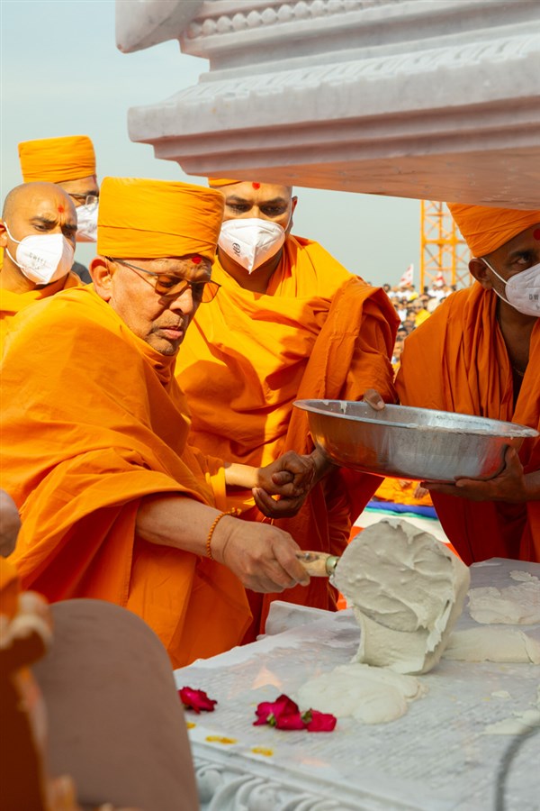 Pujya Ghanshyamcharan Swami pours cement on the pillar base