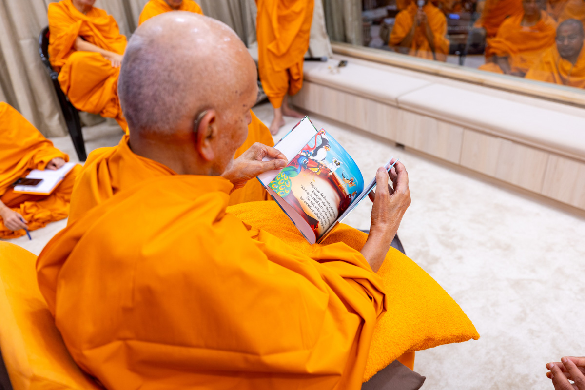 Swamishri observes a book