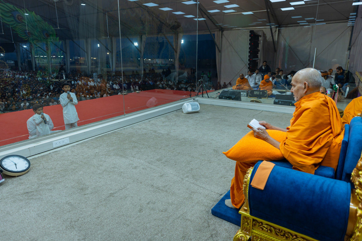 A child leads everyone in reciting the sadhana mantra and daily prayer in Swamishri's puja 