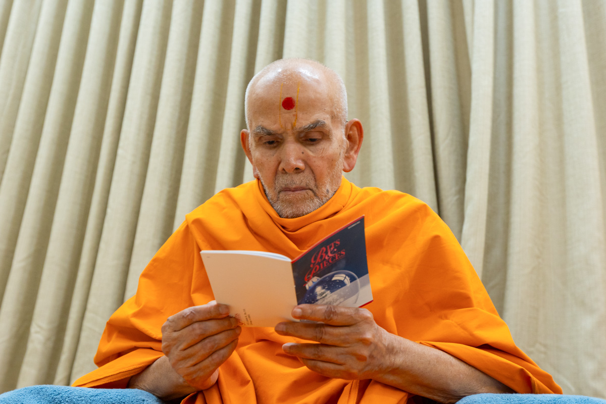 Swamishri reads an English book, 'Bits & Pieces'