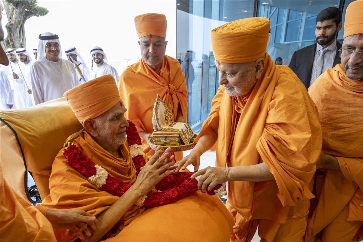 Sadguru Pujya Ishwarcharandas Swami greets Swamishri with a garland of fresh flowers