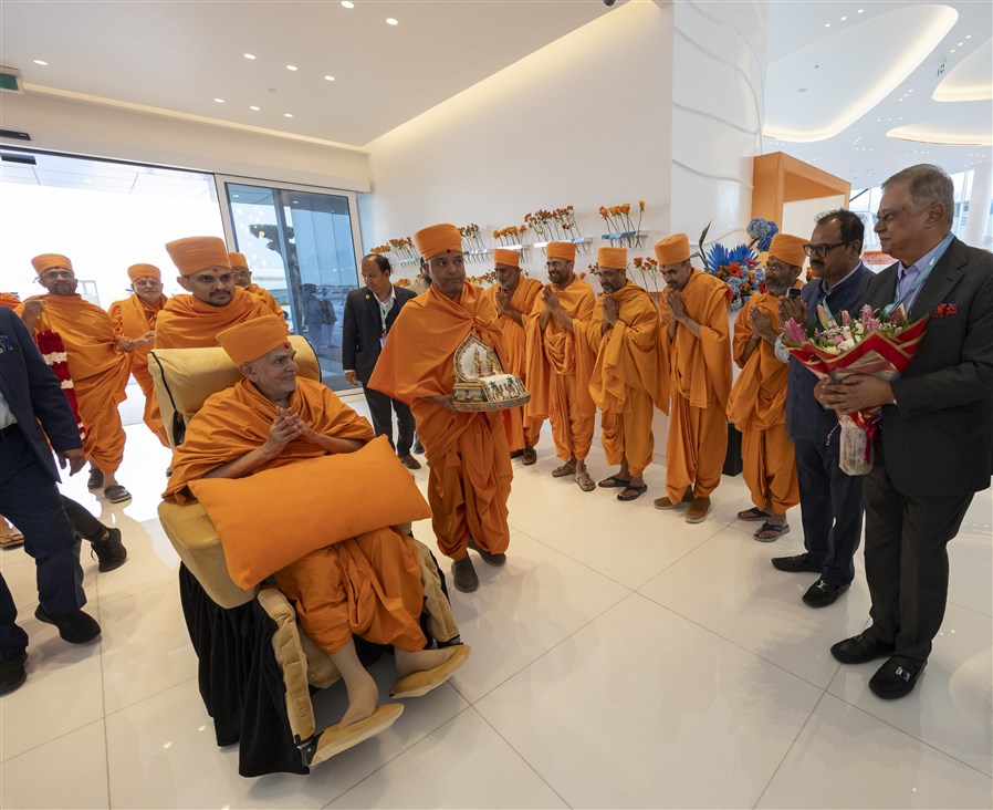 Swamishri makes his way through the airport humbly accepting the warm welcome with folded hands