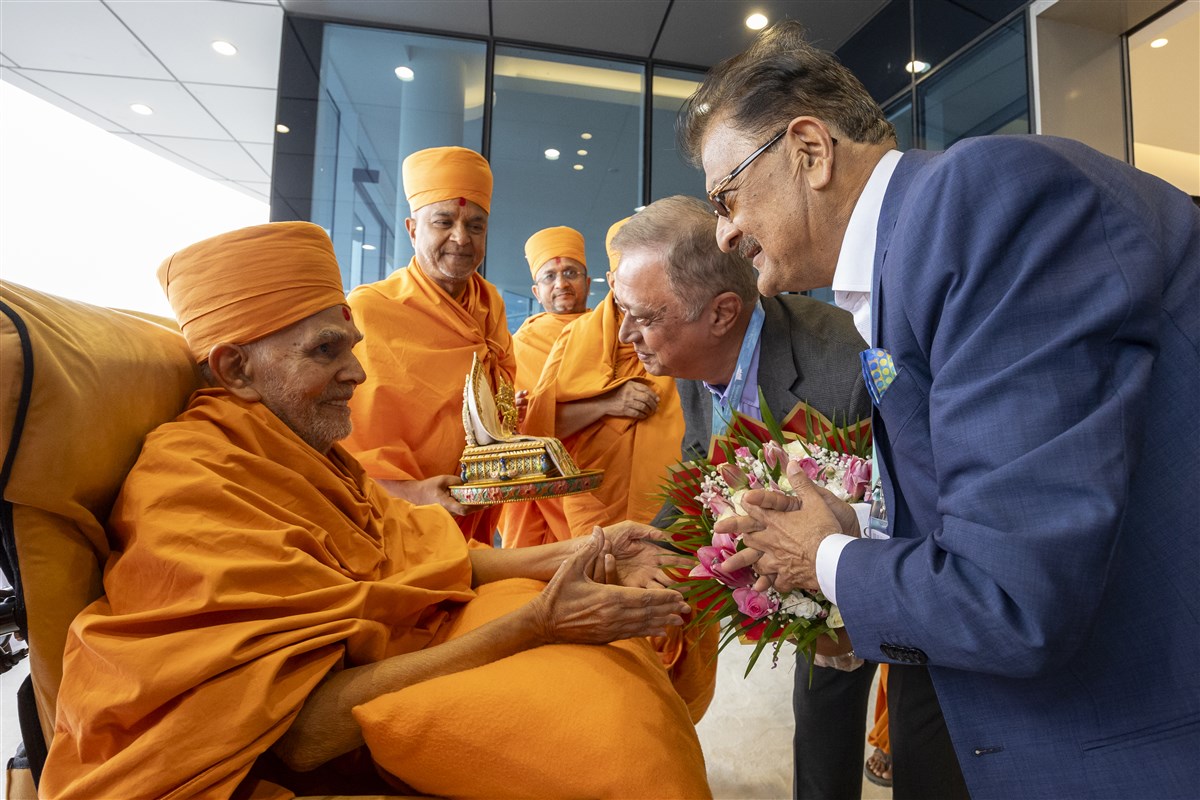 Ashok Kotecha, Chairman of BAPS UAE, and Yogesh Mehta, a leading Director of BAPS UAE, greet Swamishri with flower bouquets