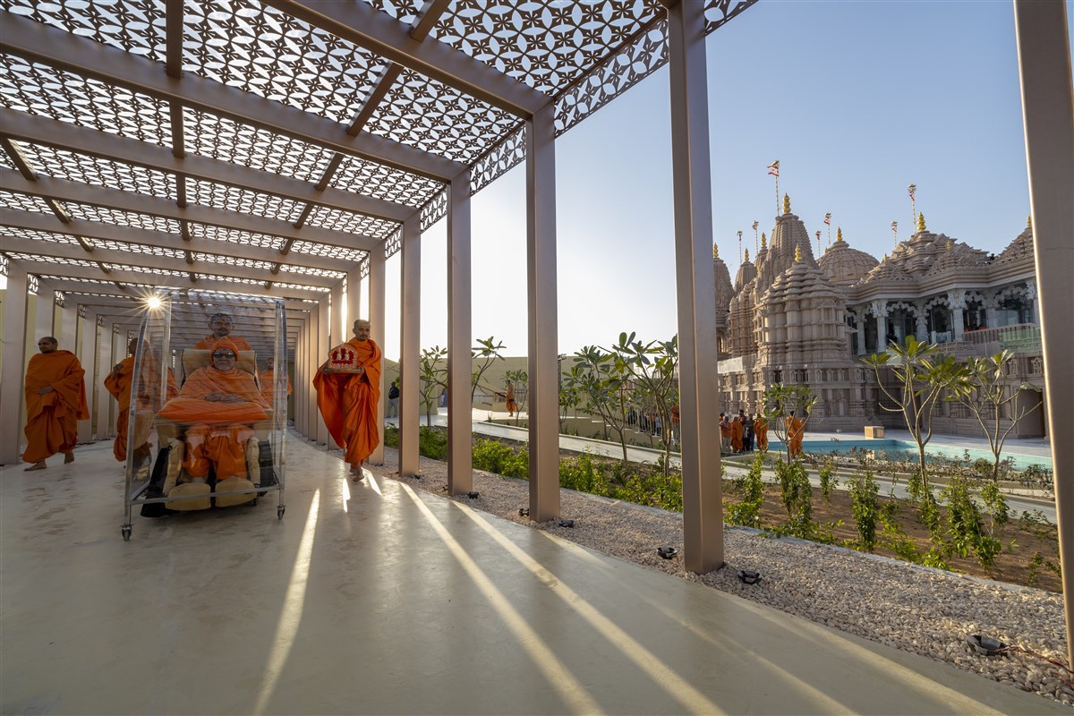 Swamishri passes along the sheltered colonnade