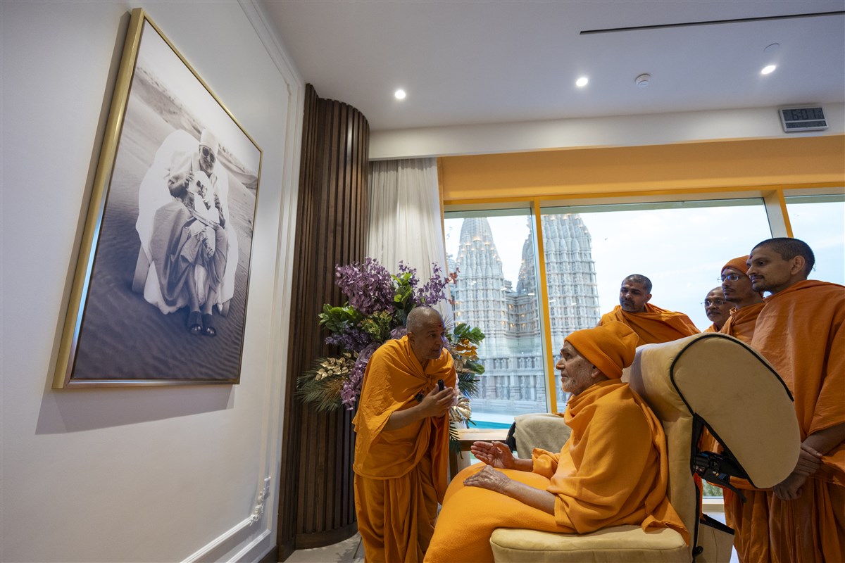 Swamishri admires a photo of Pramukh Swami Maharaj as Brahmaviharidas Swami explains its historical context