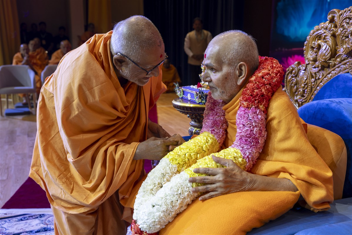 Sadguru Bhaktipriyadas Swami honours Swamishri with a garland of fresh flowers