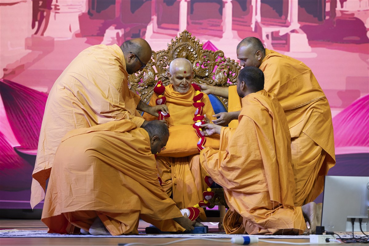 Swamis honour Swamishri with a decorative garland