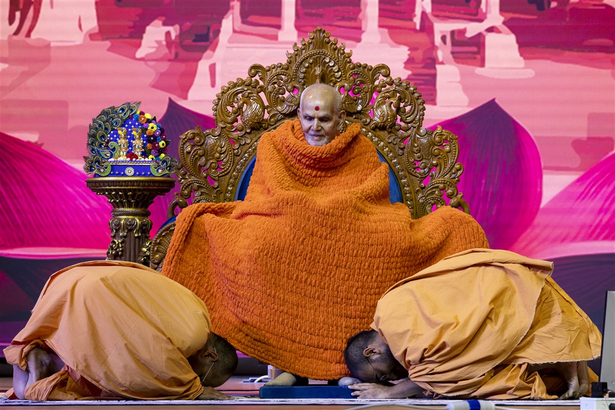 Swamishri accepts a decorative shawl from swamis as they bow before him