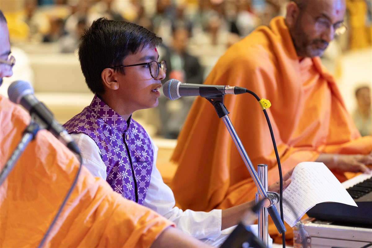 A child sings a kirtan during Swamishri's puja