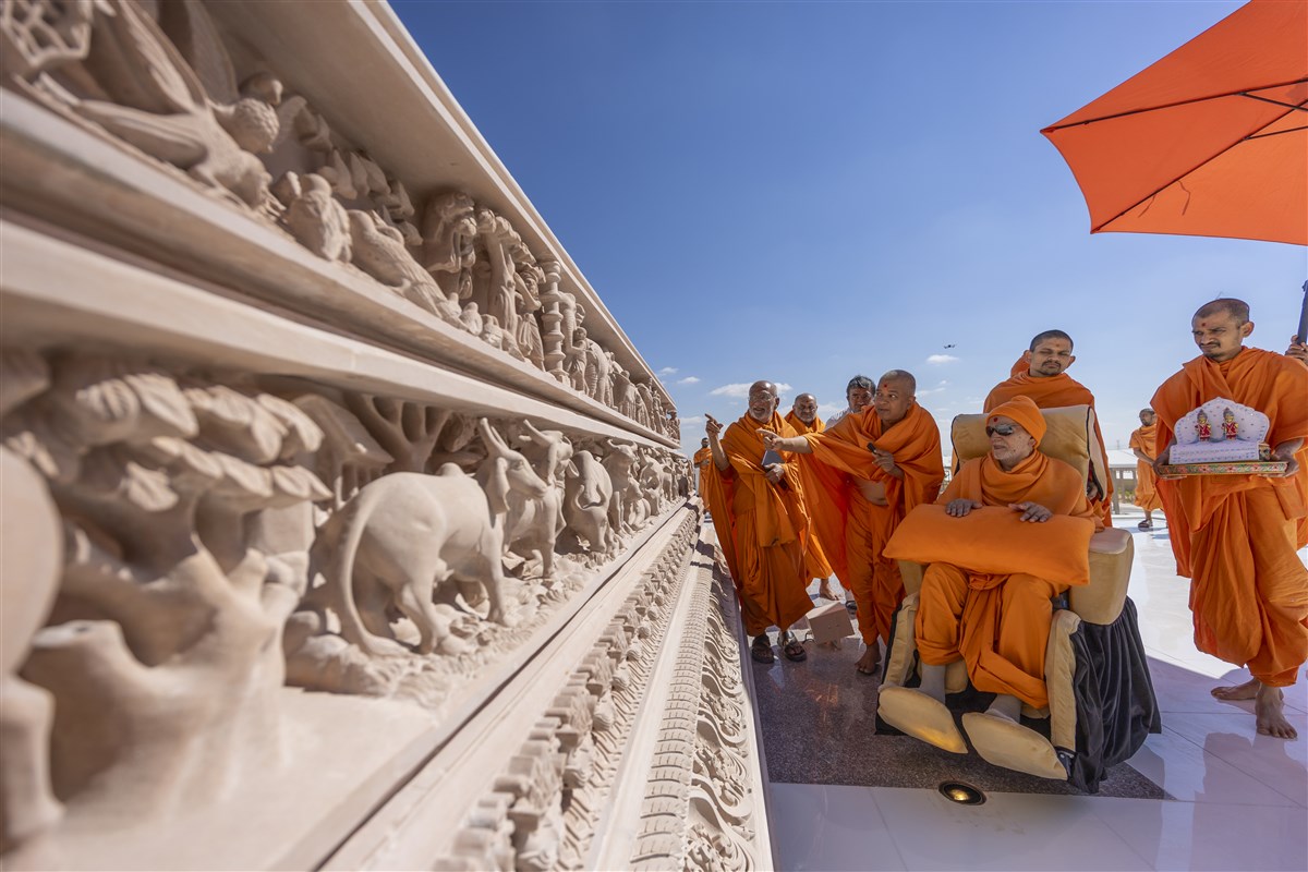 Swamishri observes the mandir's intricate carvings featuring flora and fauna from both the Indian and Arabian cultures