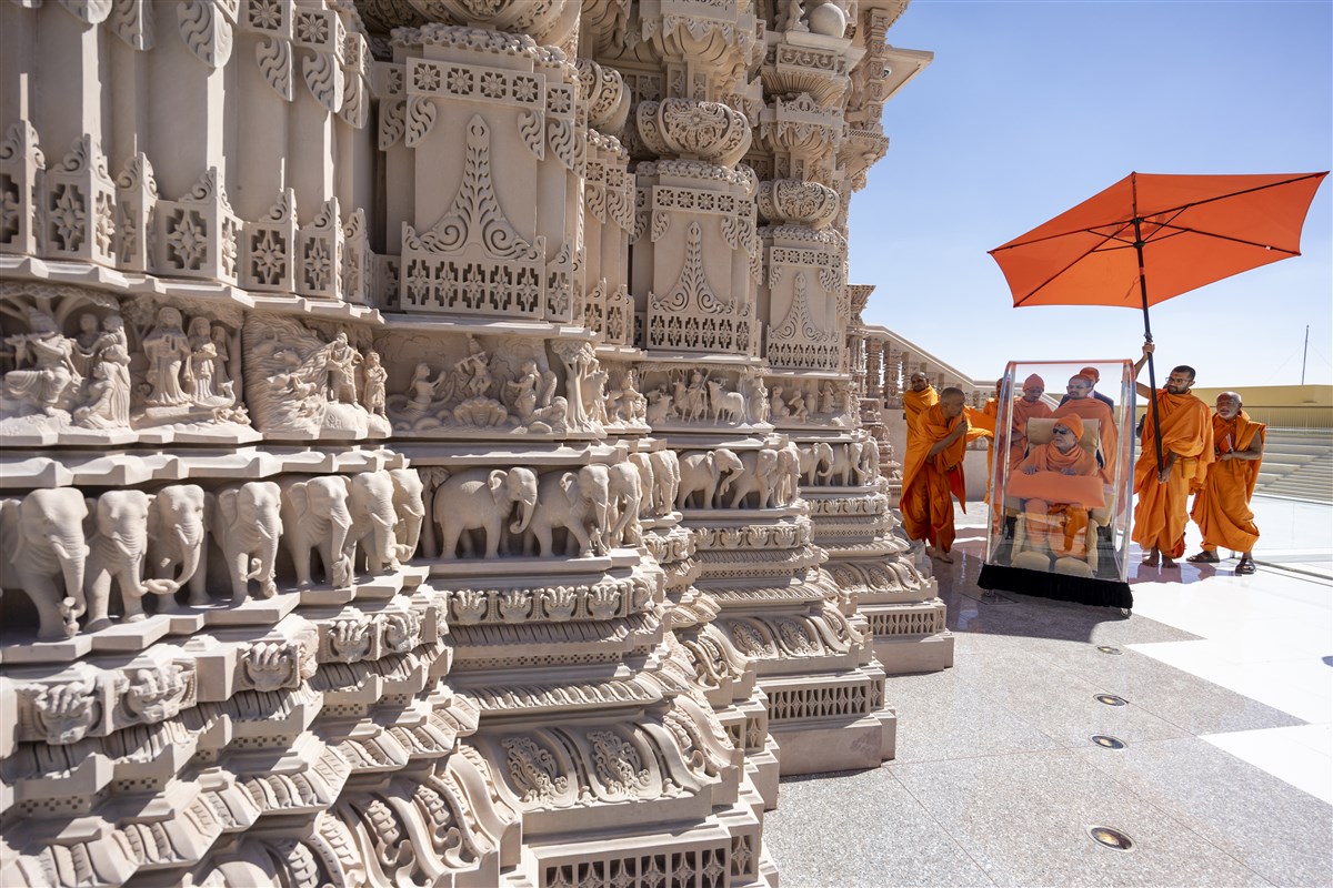 Swamishri closely observes the divine narratives from Hindu scriptures depicted in stone around the mandir's exterior