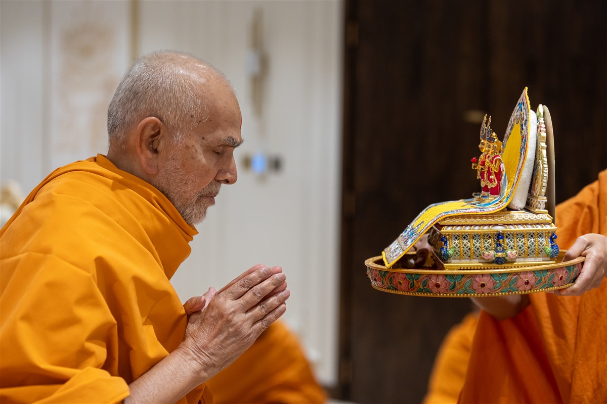 Swamishri bows with folded hands before Shri Harikrishna Maharaj and Shri Gunatitanand Swami