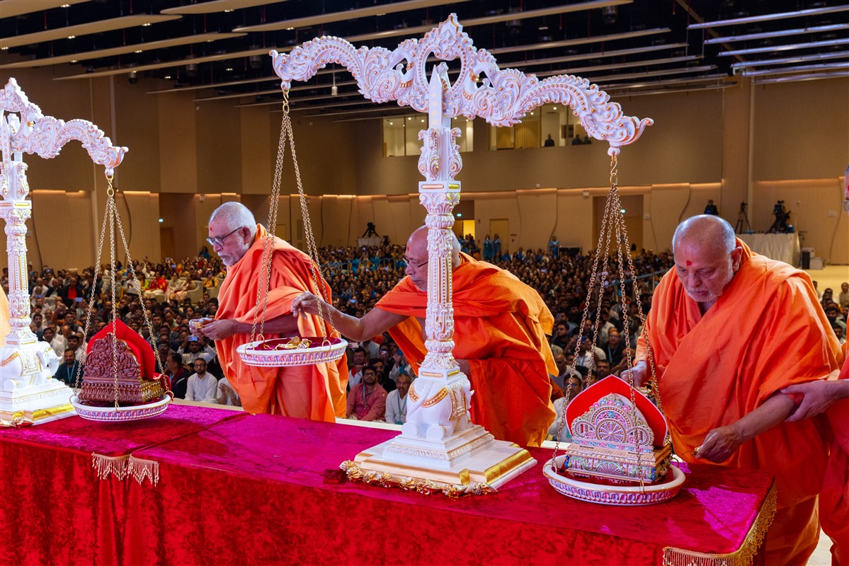 Sadguru swamis offer their devotion to Akshar-Purushottam Maharaj by placing a rosary bead bag on the sacred scales