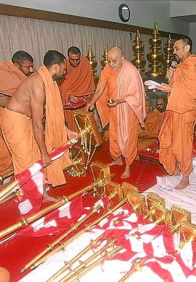 Swamishri ritually performs pujan of the flagstaffs