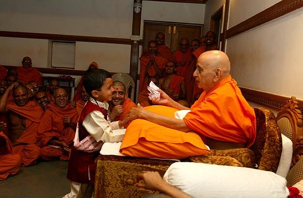 Swamishri talks to the child, gives him prasad...