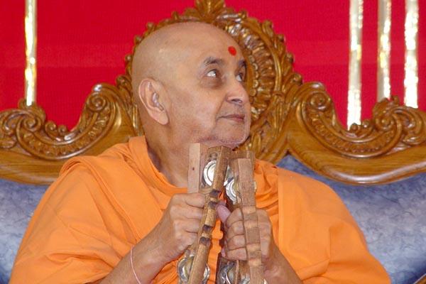 Swamishri devotionally plays the kartal in an assembly