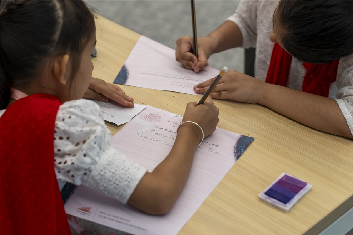 Young girls write their personal prayers to His Holiness Mahant Swami Maharaj