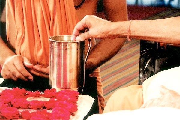 Swamishri sanctifies water with a rosary bead used by Shriji Maharaj