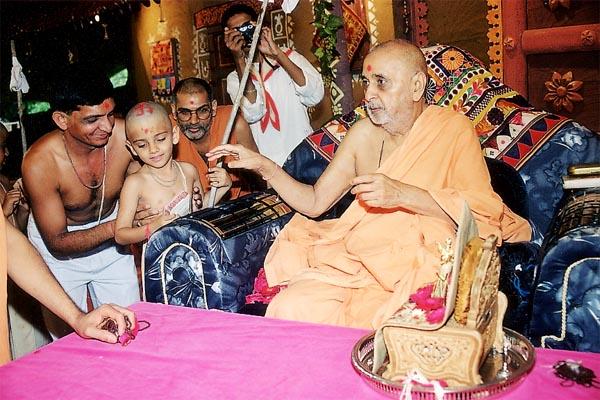 Swamishri conducts the sacred thread ritual for a boy