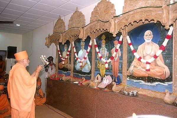 Swamishri performs the murti-pratishtha arti in the assembly hall of chhatralay